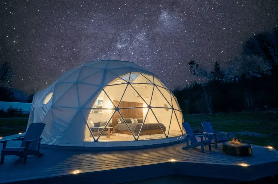 A lit geodesic dome on a timber deck under a starry night sky